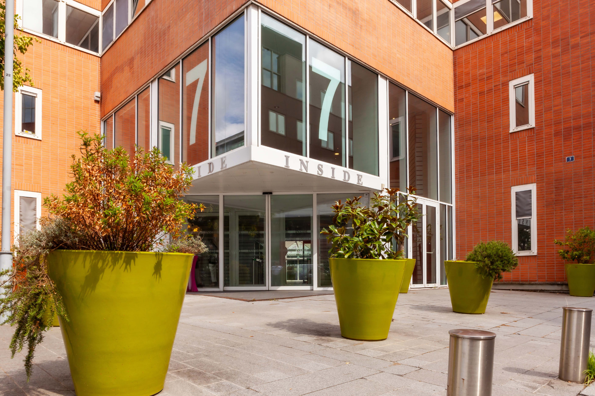 CLS Inside — close-up of the Inside 7 glass corner entrance with chartreuse planters