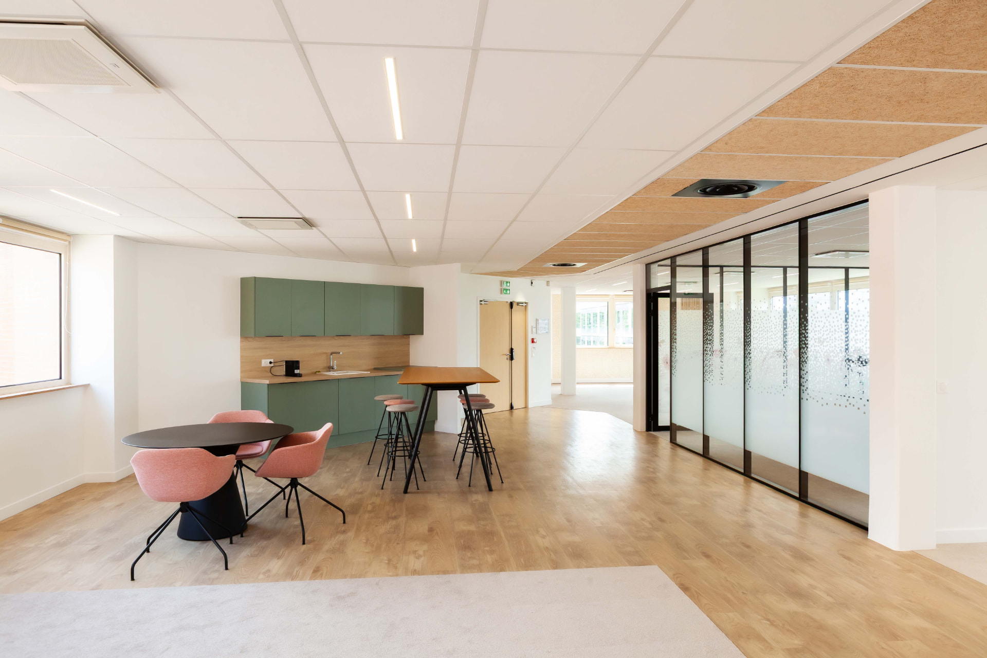 CLS Inside — shared kitchen area with sage green units, round table with pink chairs and a high wooden table