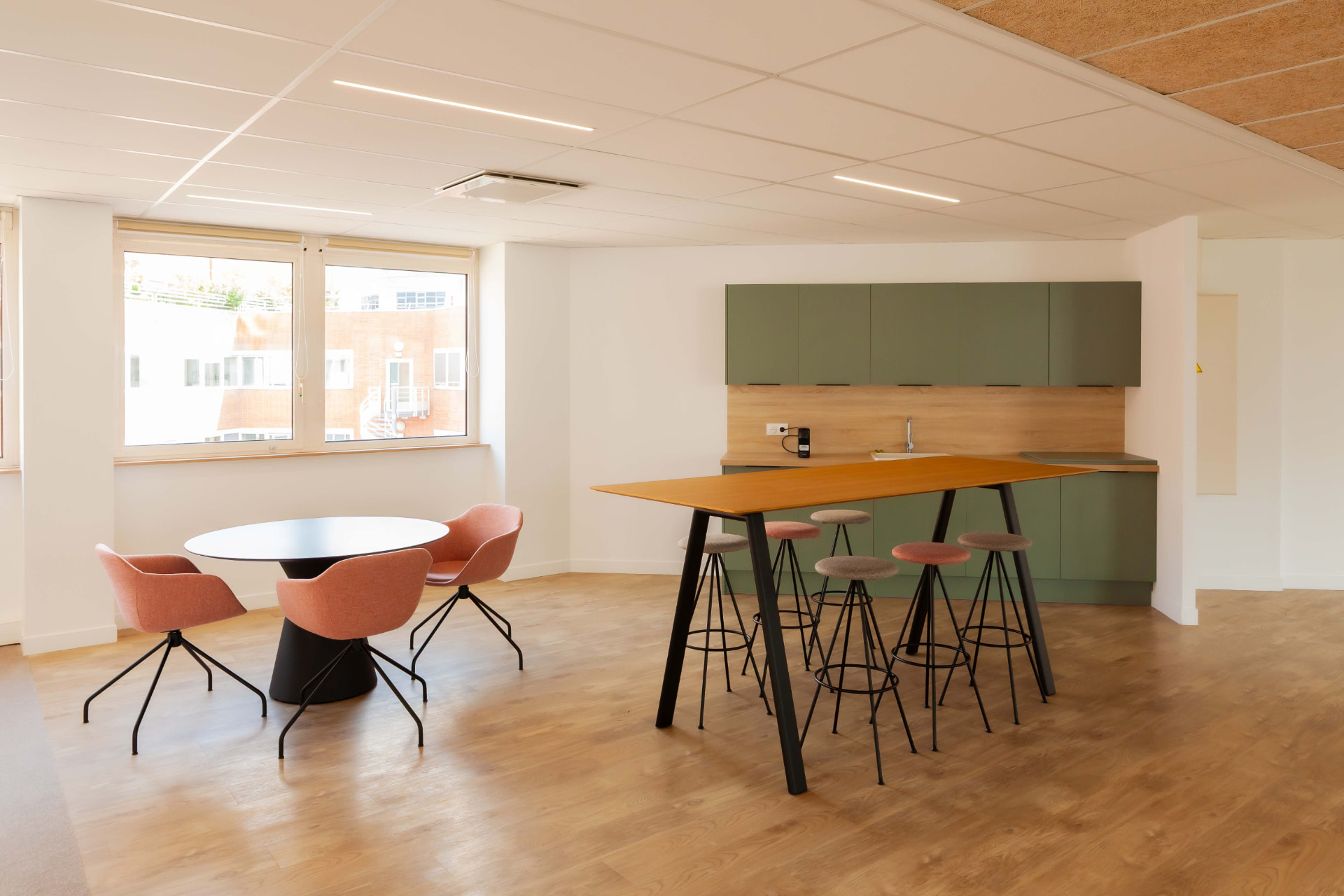 CLS Inside — breakroom with coral armchairs, high-top table and olive green kitchenette