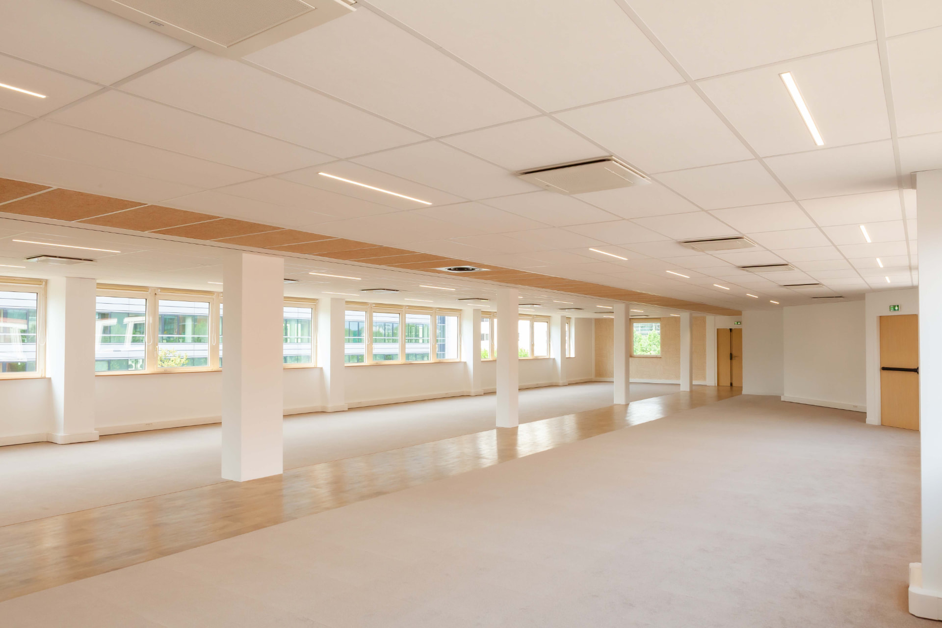 CLS Inside — empty open-plan office floor with white columns and a row of windows