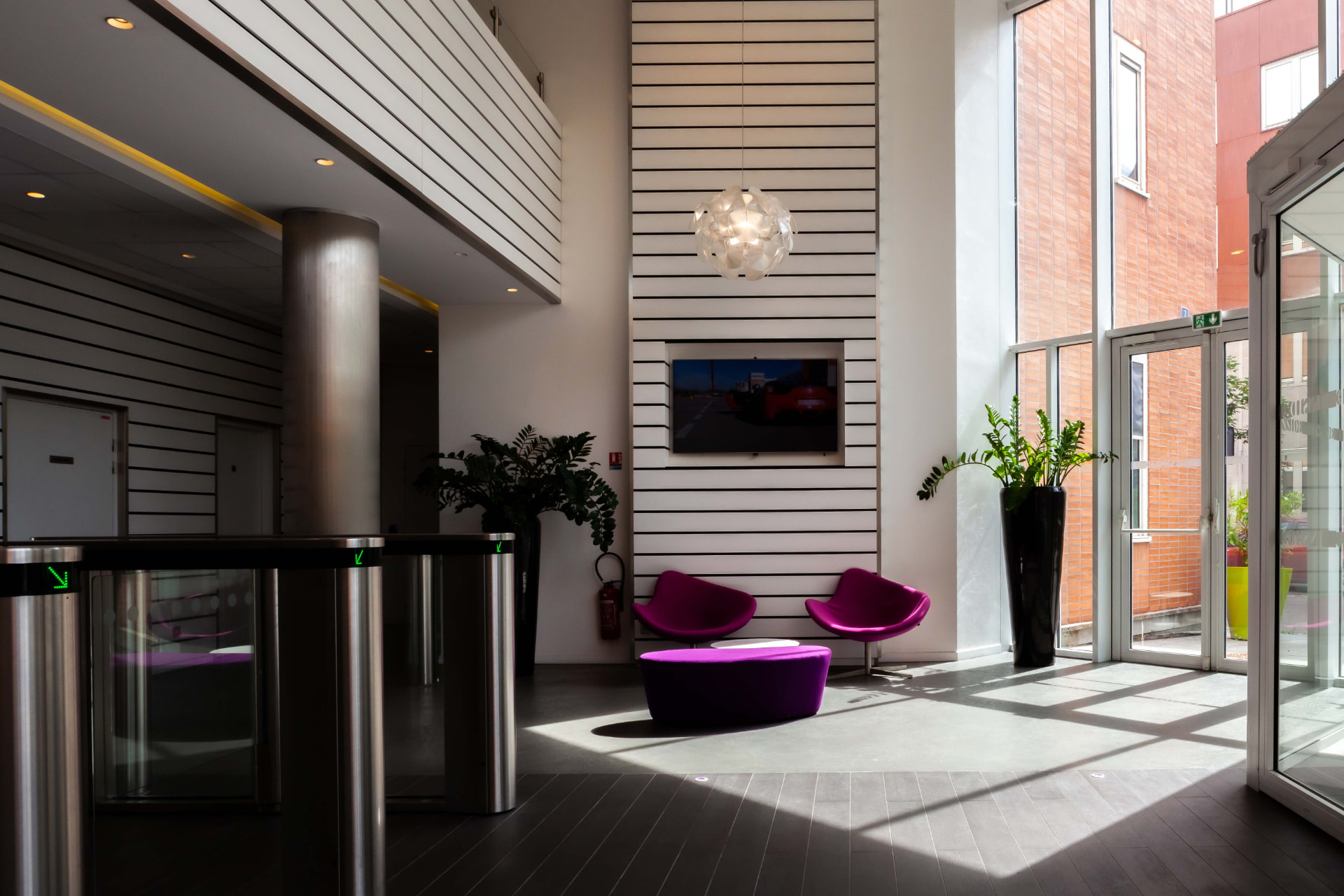 CLS Inside — sunlit lobby with security turnstiles, magenta seating and brick views