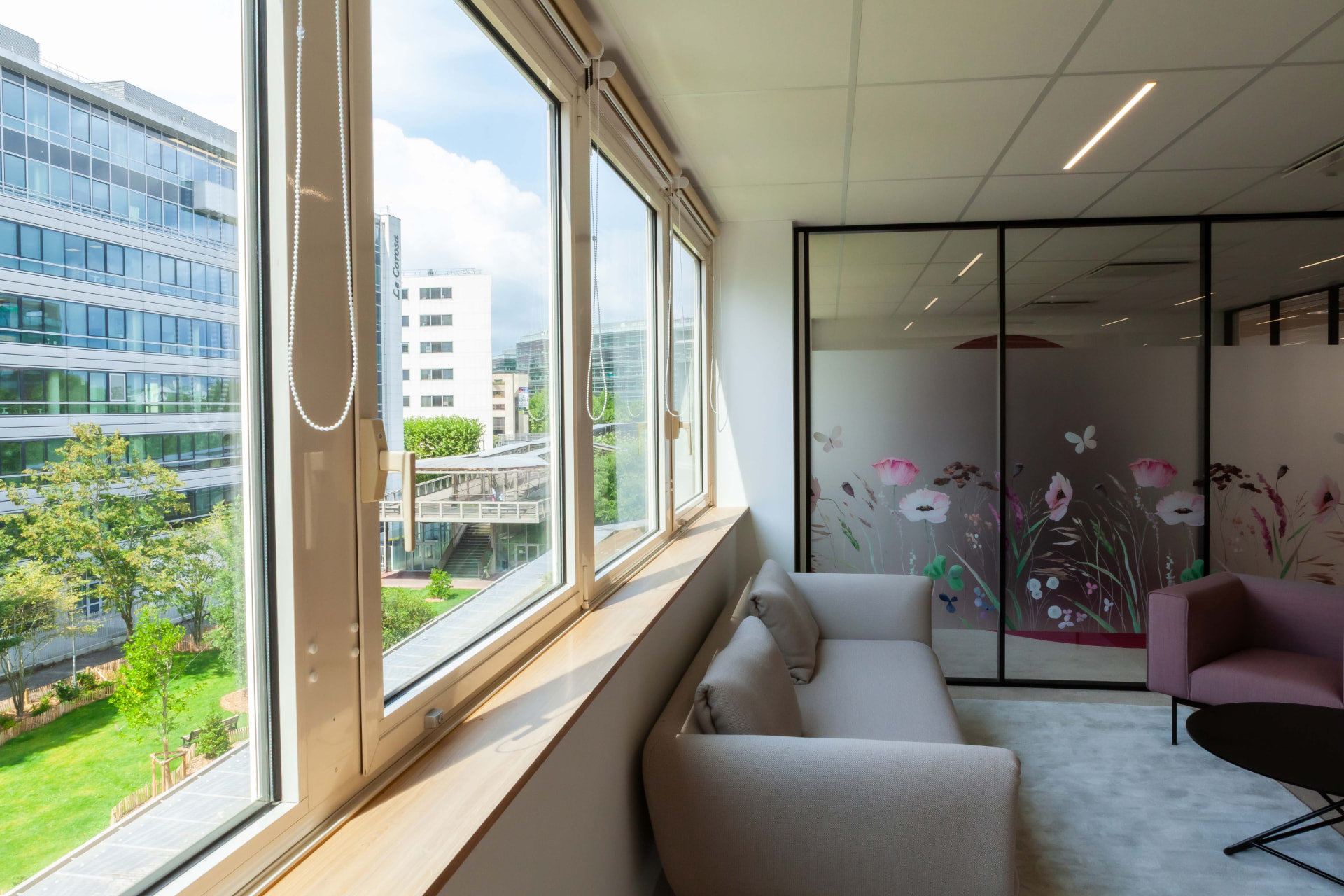 CLS Inside — sofa and armchair by tall windows looking out over a green courtyard