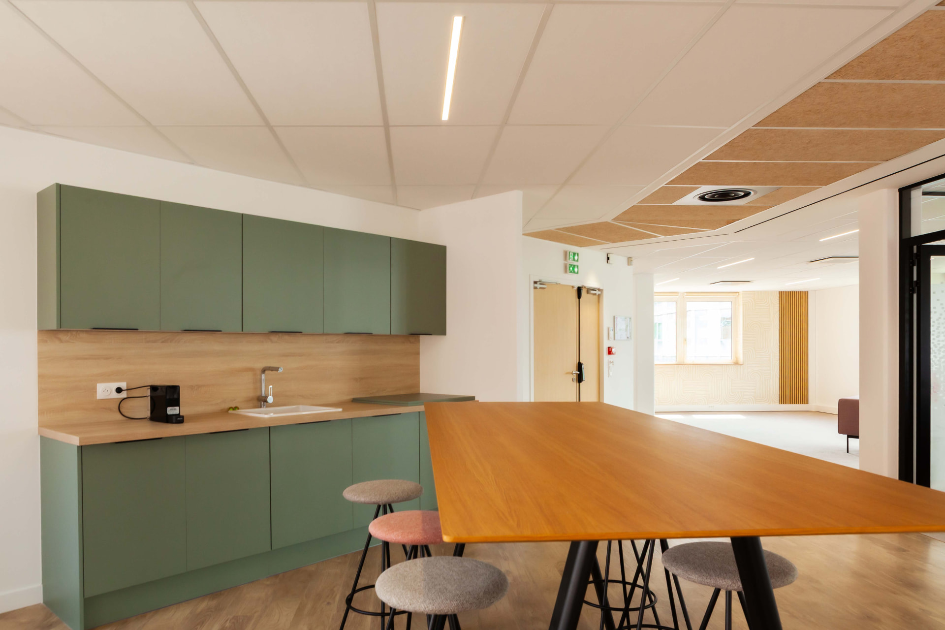 CLS Inside — sage green kitchenette with wood worktop and stools at the high table