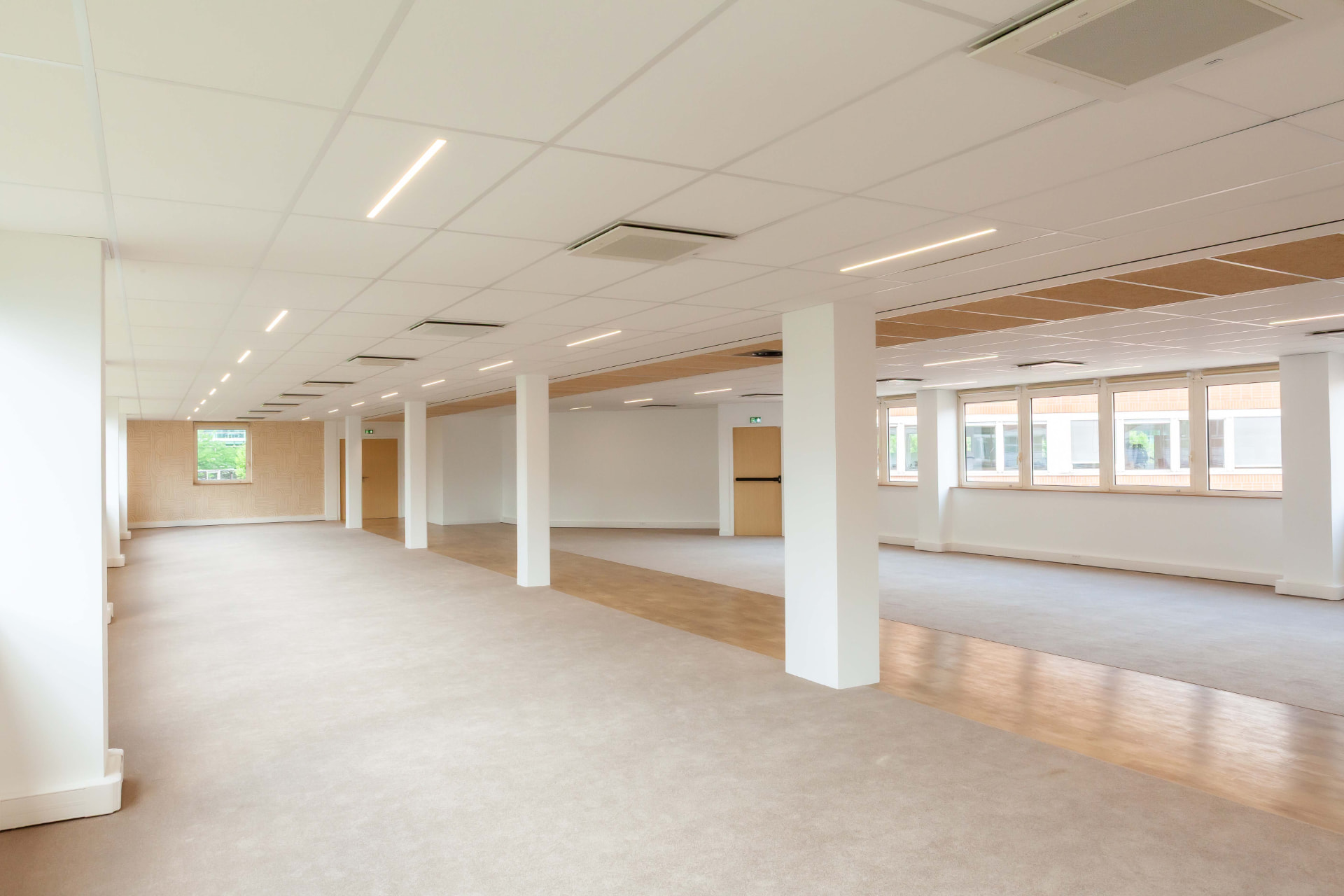 CLS Inside — empty open-plan office floor with a row of white pillars and a wall of windows