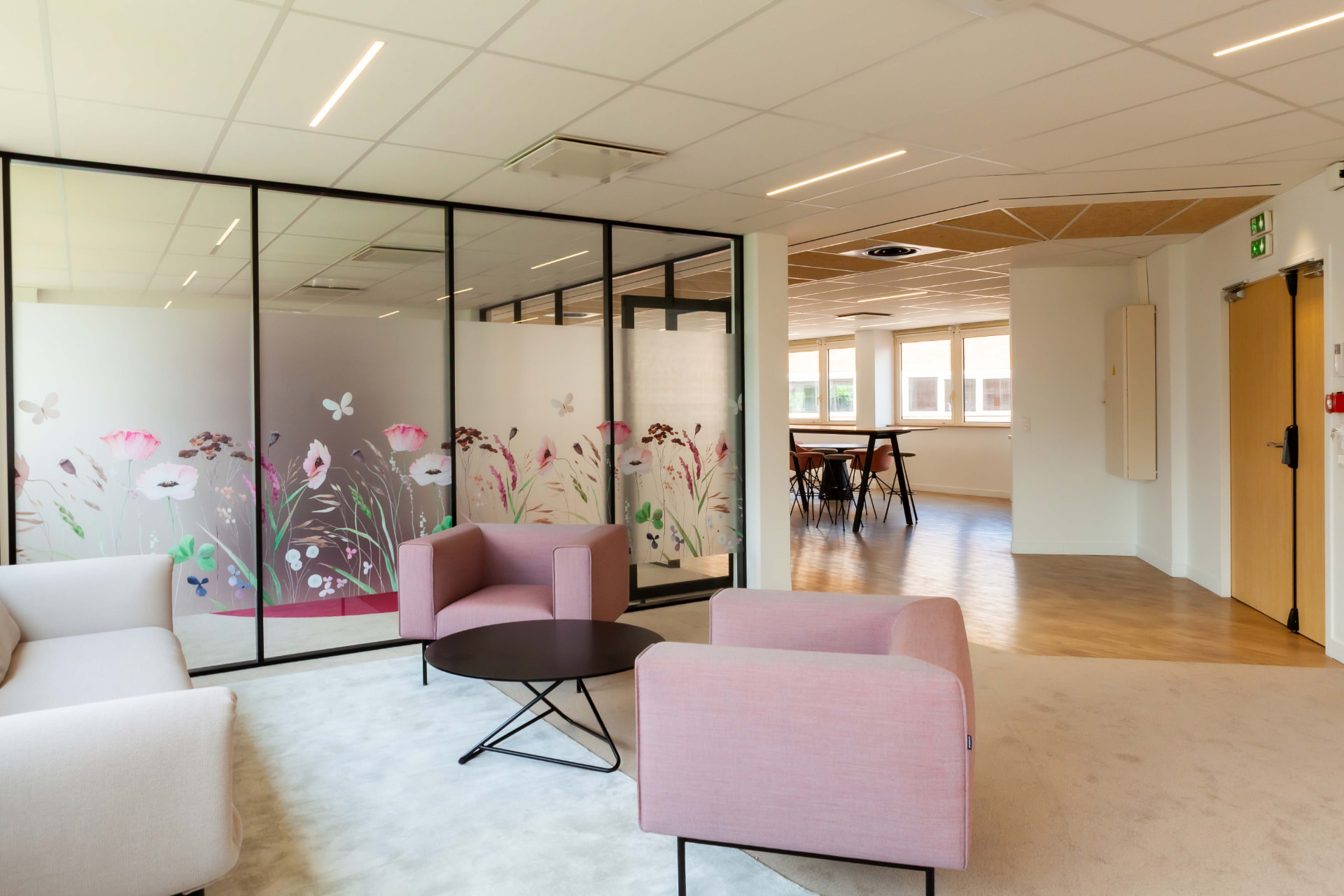 CLS Inside — lounge seating in front of floral glass partitions opening onto a bright hallway