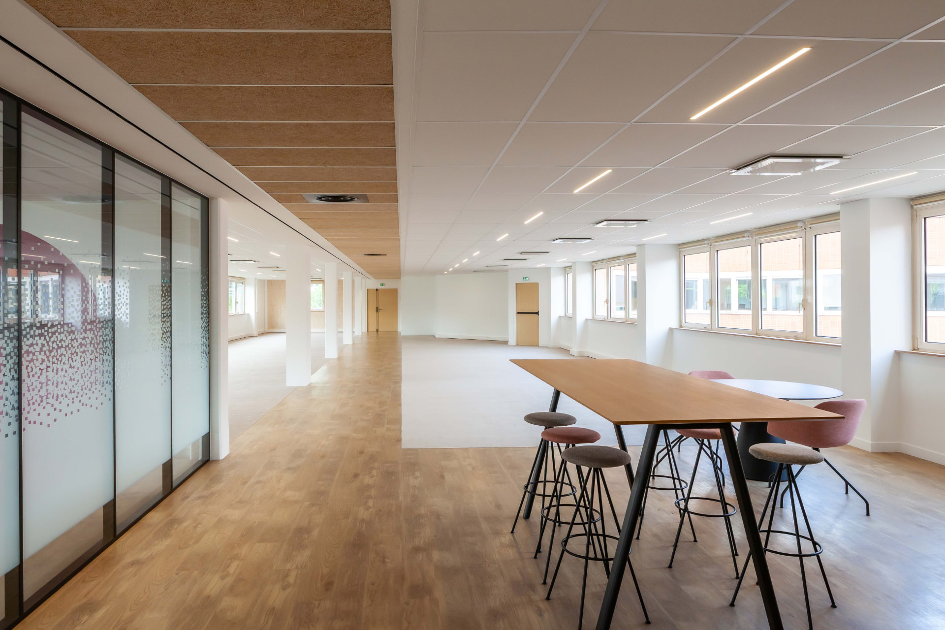CLS Inside — office walkway with high meeting table and frosted pixel-pattern glass wall